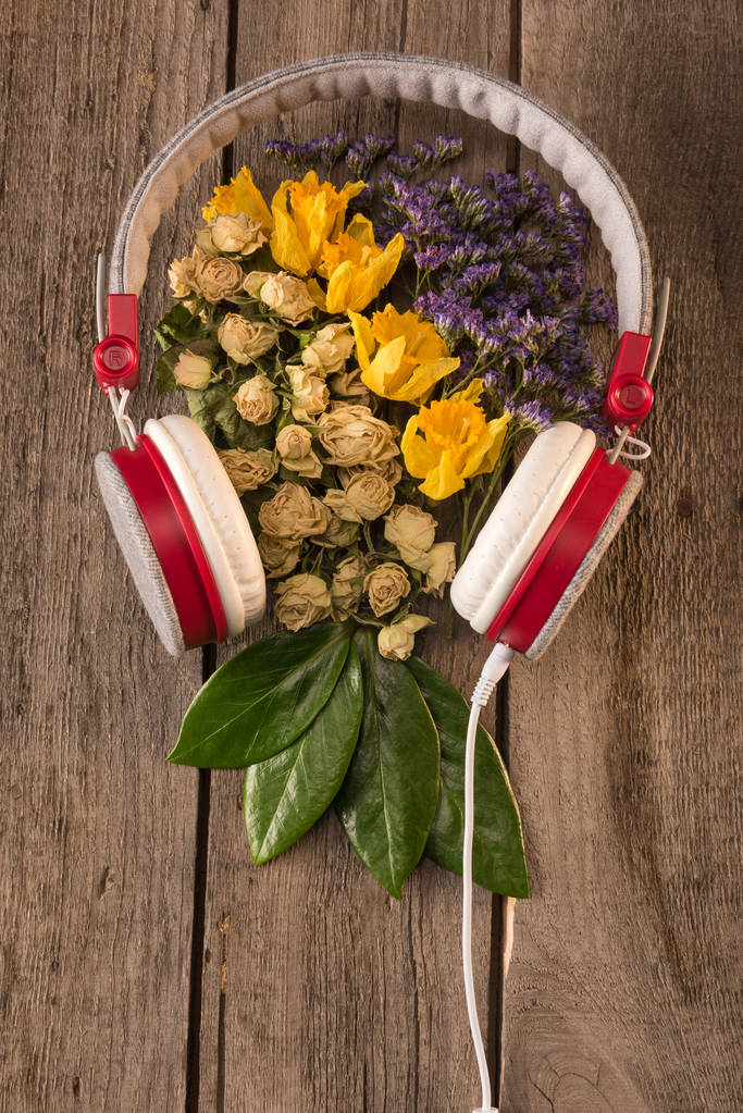 hoofdtelefoons en bloemen op tafel - Foto, afbeelding