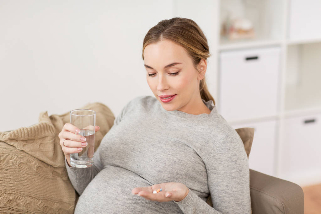 Glückliche Schwangere mit Wasser und Pillen zu Hause - Foto, Bild