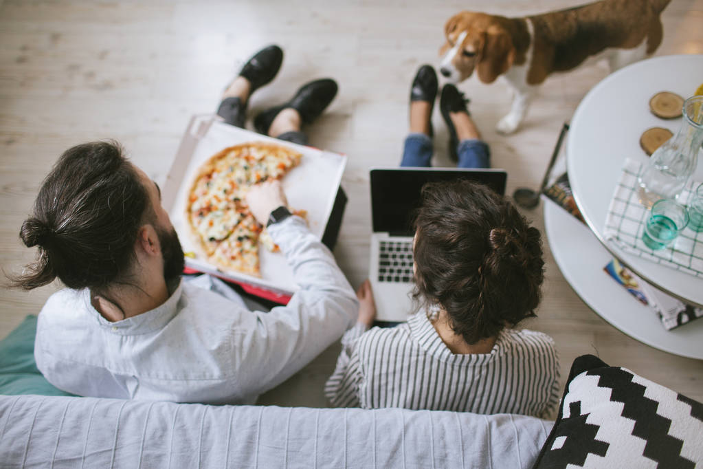 Mladí bokovky pár domů, jíst pizzu s notebookem a pes - Fotografie, Obrázek