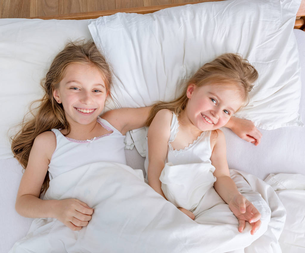 dwie małe piękne siostry w białe łóżko - Zdjęcie, obraz