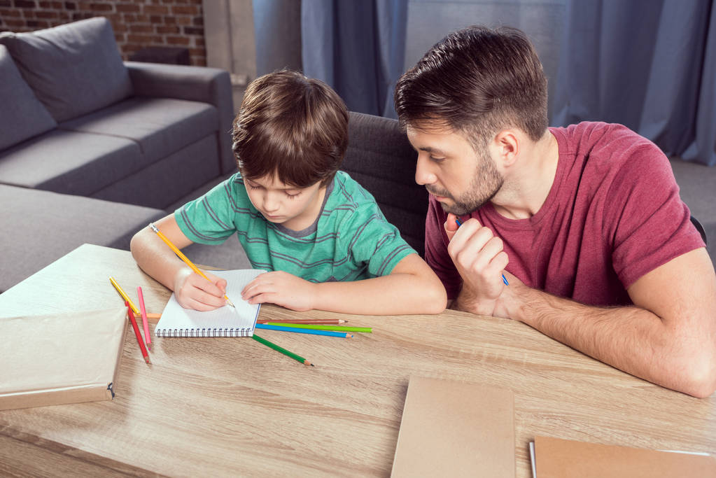 Apa segít a fiának házi feladatot csinálni.  - Fotó, kép
