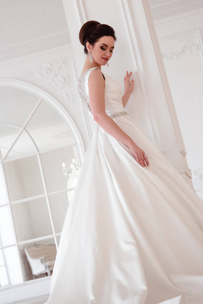 Porträt der schönen brünetten Braut mit eleganter Frisur und Make-up trägt lange Luxus-Hochzeitskleid - Foto, Bild