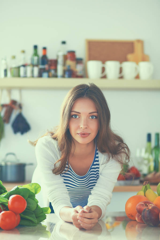 Молодая женщина, стоящая возле стола на кухне - Фото, изображение