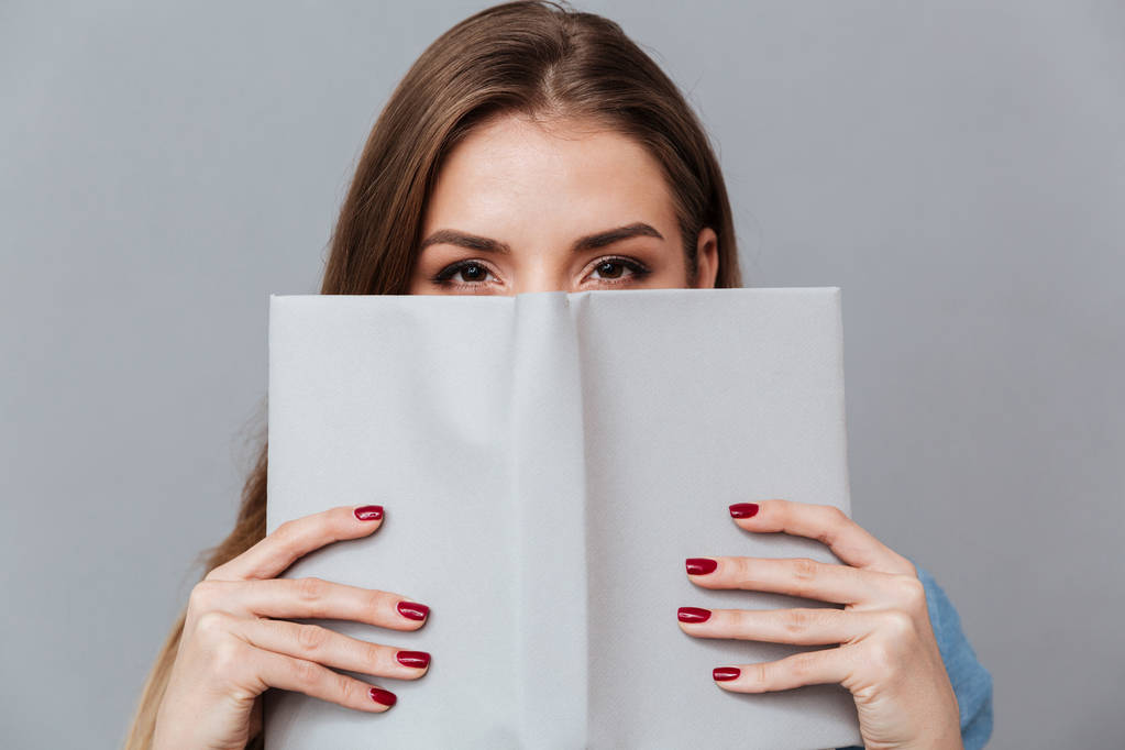 Vrouw in hemd verstopt achter het boek - Foto, afbeelding