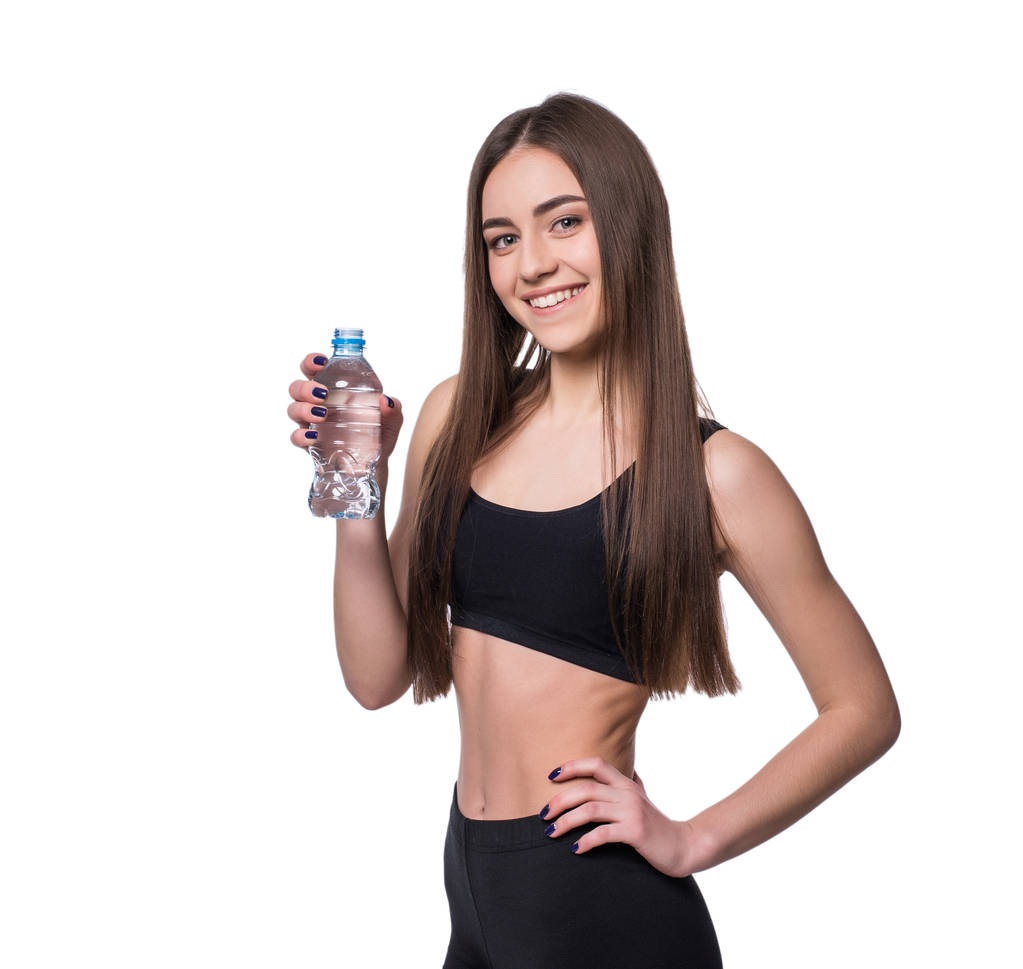 Позитивная женская фитнес-модель после тренировки с бутылкой чистой воды на белом фоне
. - Фото, изображение