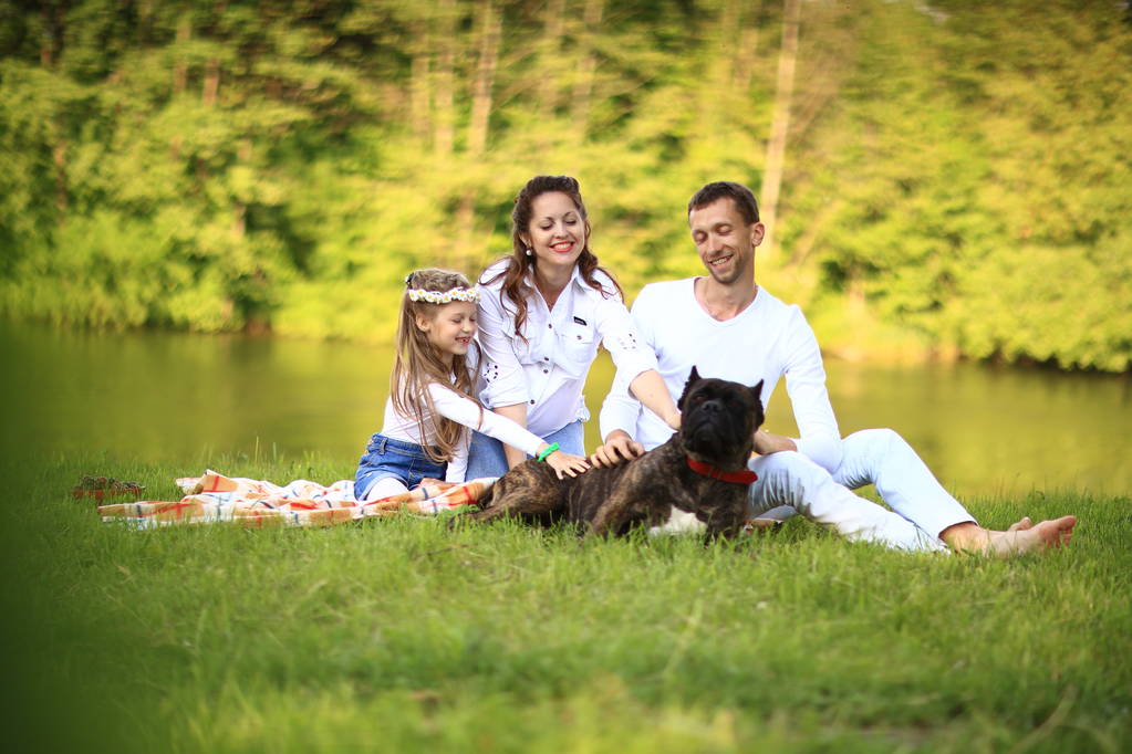 familia feliz con perro mascota en el picnic en un día soleado de verano. pregn - Foto, imagen