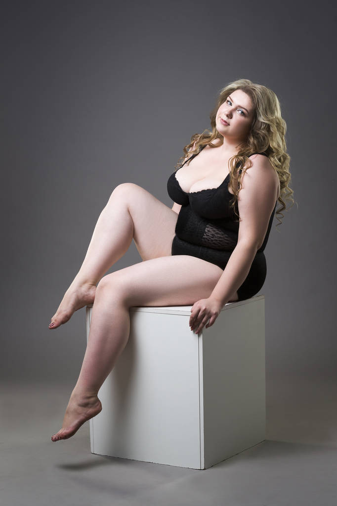 Junge schöne Blondine plus Size-Modell in Shapewear, XL-Frau in schlanker Unterwäsche auf grauem Studiohintergrund - Foto, Bild