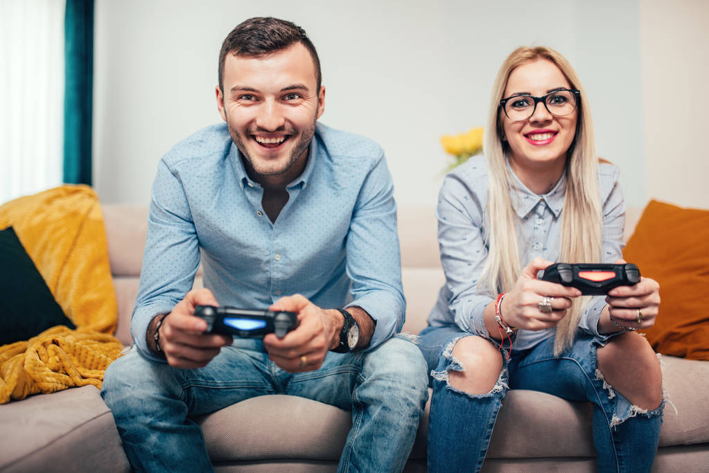 Νεαρό παντρεμένο ζευγάρι παίζοντας βιντεοπαιχνίδια στην κονσόλα τυχερού παιχνιδιού γενικά. Λεπτομέρειες του σύγχρονου τρόπου ζωής με ζευγάρι έχει τη διασκέδαση - Φωτογραφία, εικόνα