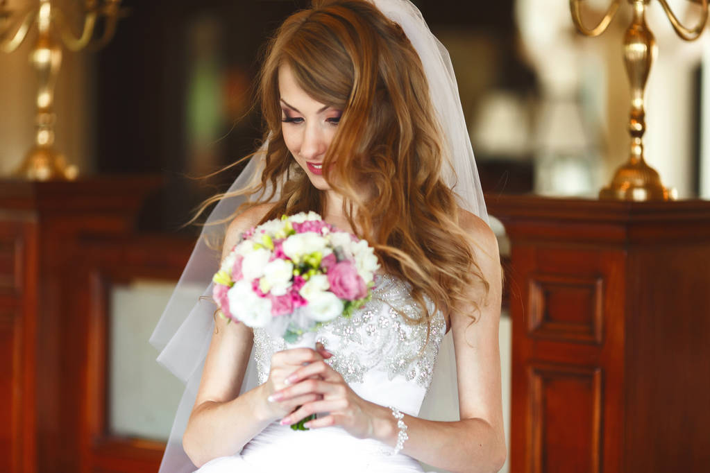 Bride mixes her hair and holds wedding bouquet in her arms  - Photo, Image