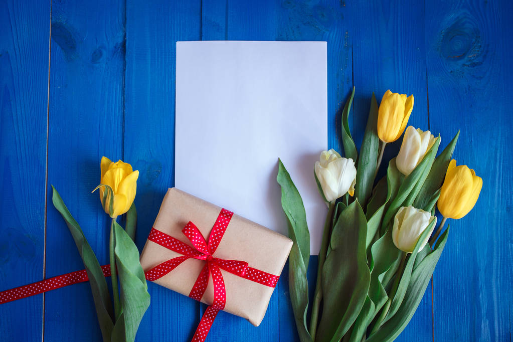 Jarní Tulipán květiny, dárkové krabice a papír kartu na modré dřevěný stůl z výšky v ploché laických stylu.  - Fotografie, Obrázek