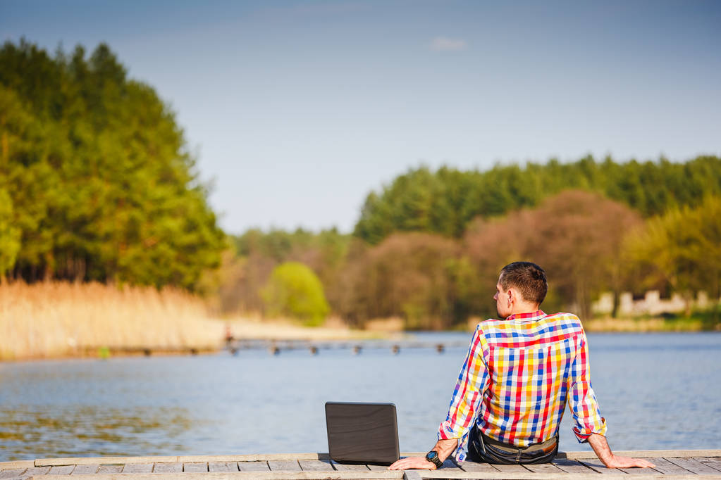 Jonge man met laptop werken buiten - Foto, afbeelding