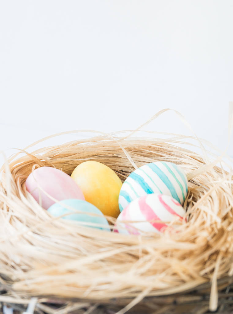 Uova di Pasqua colorate isolate sullo sfondo bianco con nido e ghirlanda. Focus selettivo
. - Foto, immagini