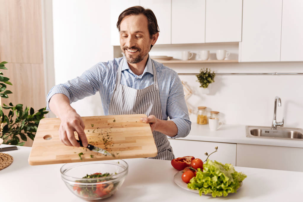 Ικανοποιημένοι γενειοφόρος άνδρας μαγείρεμα σαλάτα λαχανικών  - Φωτογραφία, εικόνα