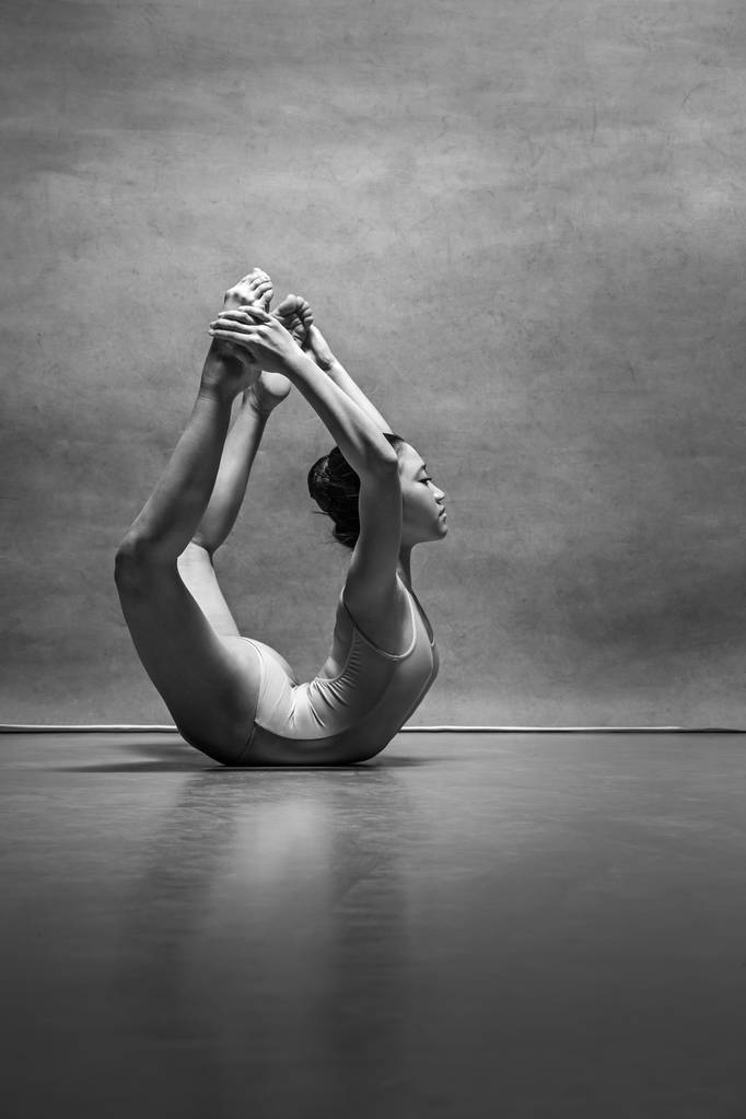 The female ballet dancer posing over gray background - Photo, Image