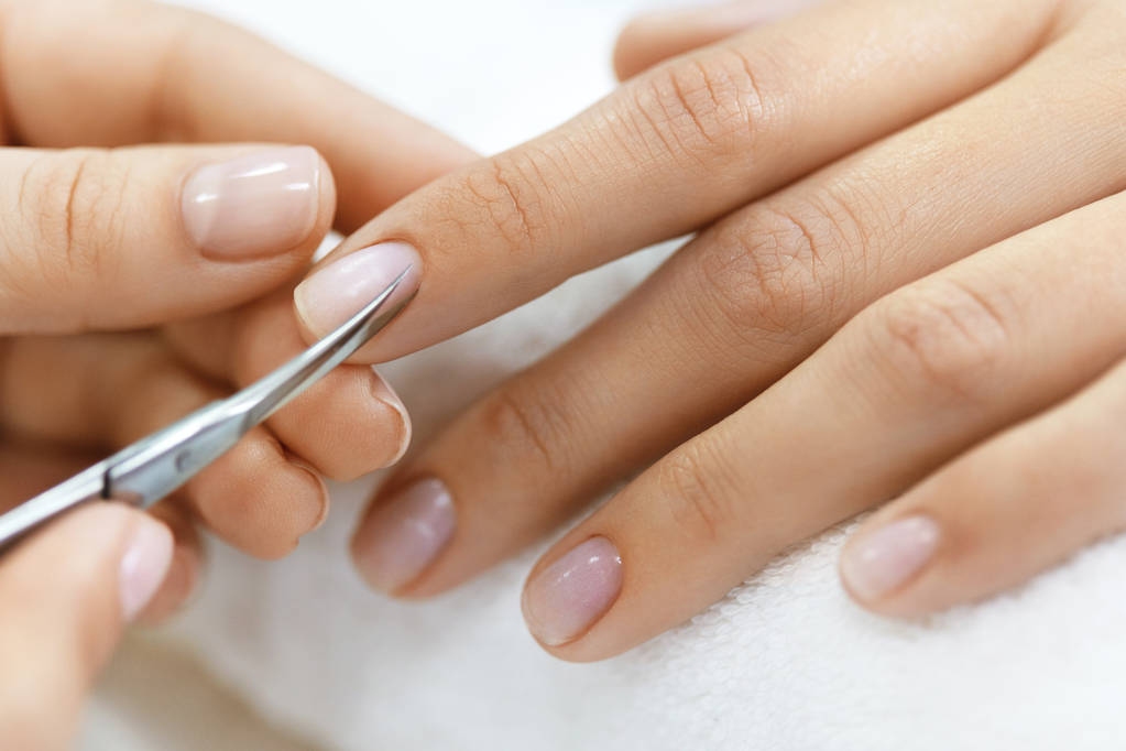 Maniküre. Hände entfernen Nagelhaut aus Frauenhand mit Schere - Foto, Bild