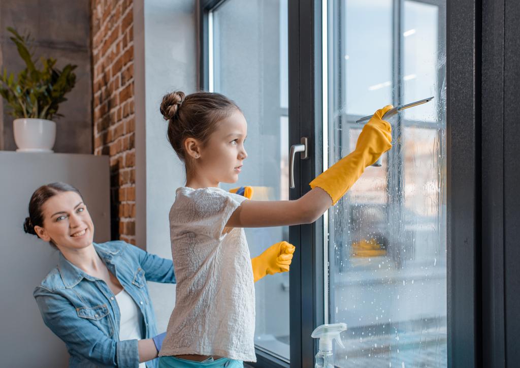 Moeder en dochter schoonmaken van venster  - Foto, afbeelding