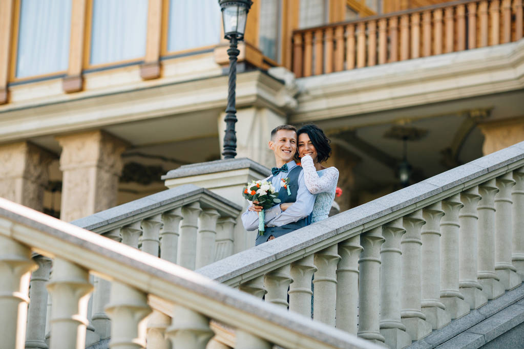 Ευτυχισμένη νύφη και τον γαμπρό αγκάλιασμα στις σκάλες του αρχοντικού - Φωτογραφία, εικόνα