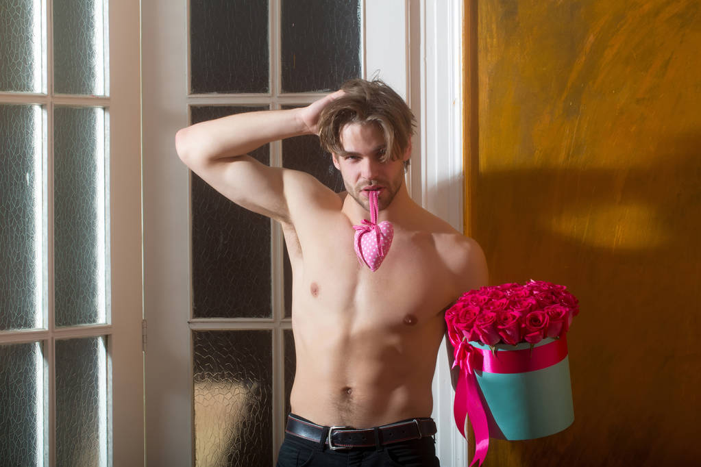 бородатий м'язистий чоловік з сексуальним тілом тримає червону коробку троянд
 - Фото, зображення