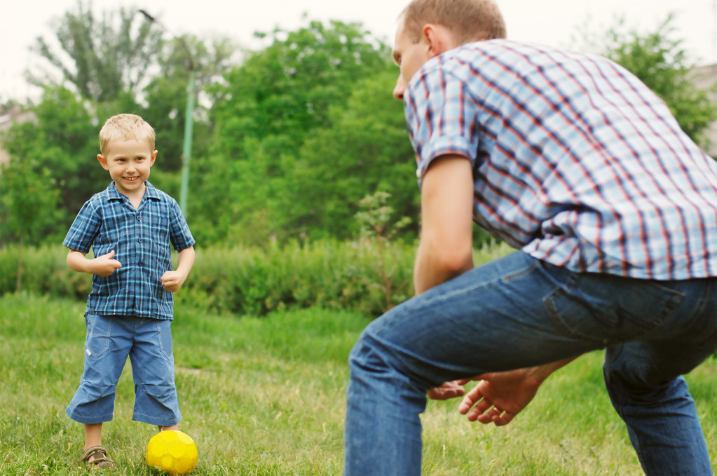 zoon en vader spelen in het voetbal - Foto, afbeelding