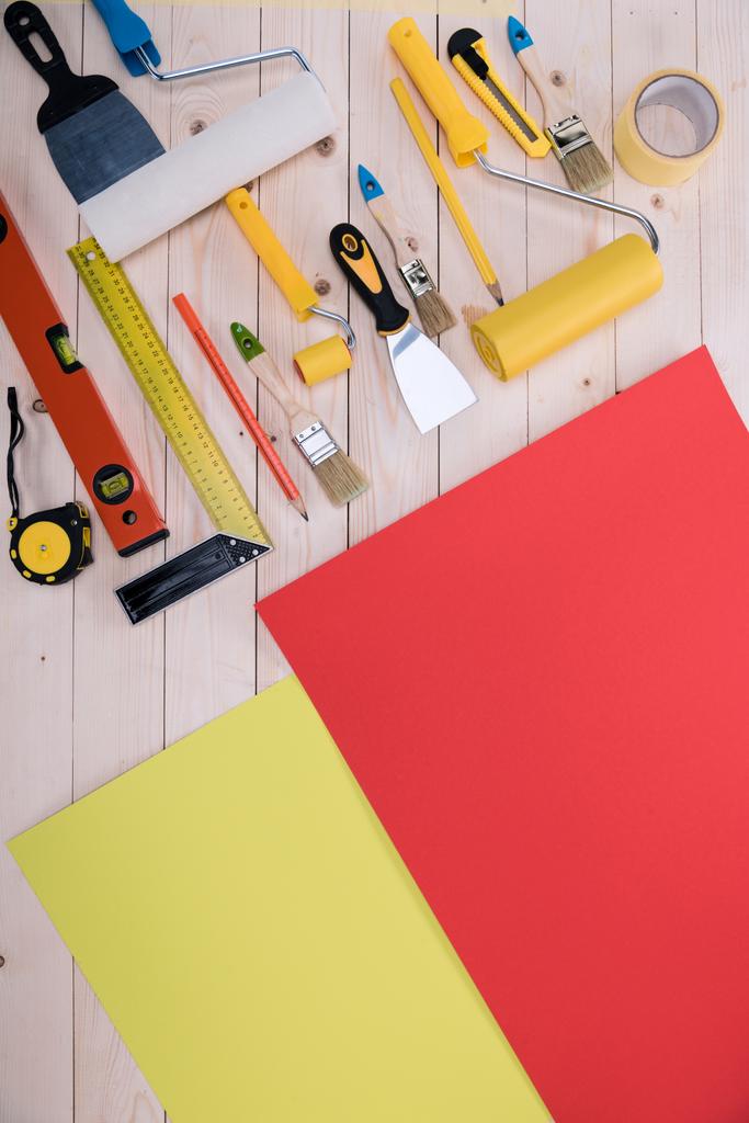 Vista superior del conjunto de herramientas de construcción y papel de color en la mesa de madera
 - Foto, Imagen