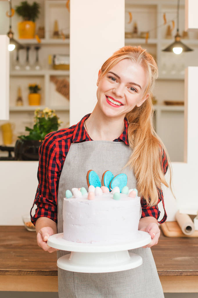 Chica con pastel blanco en la cocina. Postres de cocina
. - Foto, Imagen