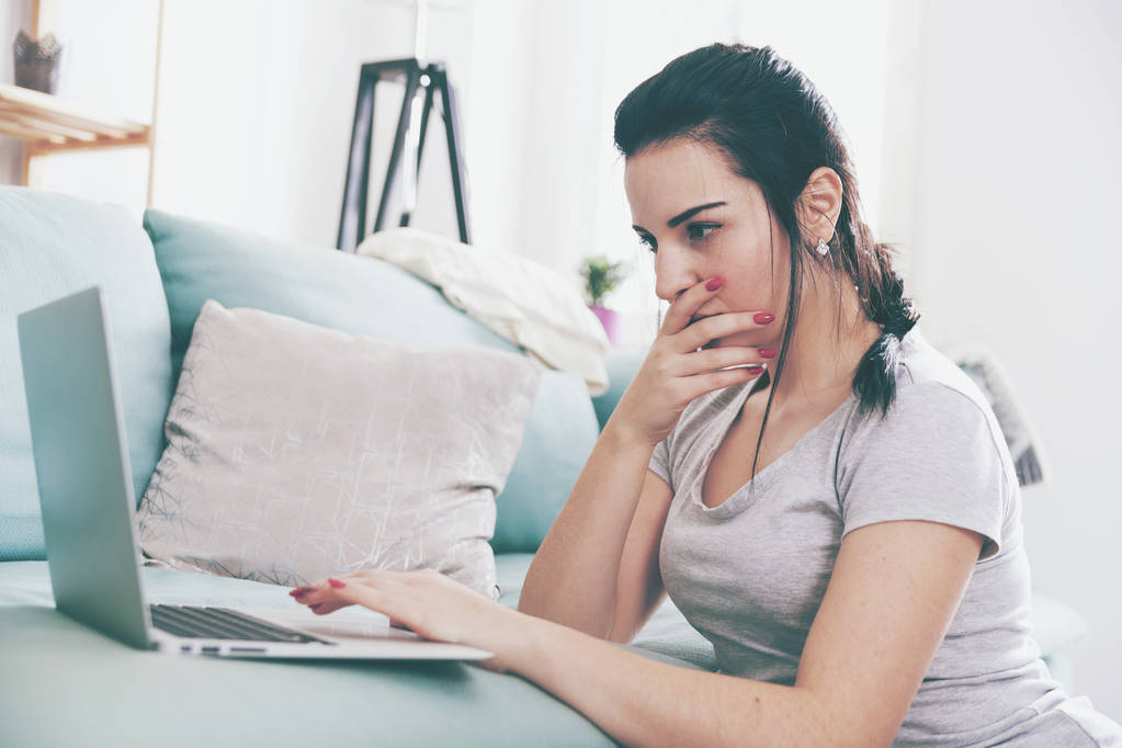 Young woman using laptop while sitting near comfortable sofa, home - Photo, Image