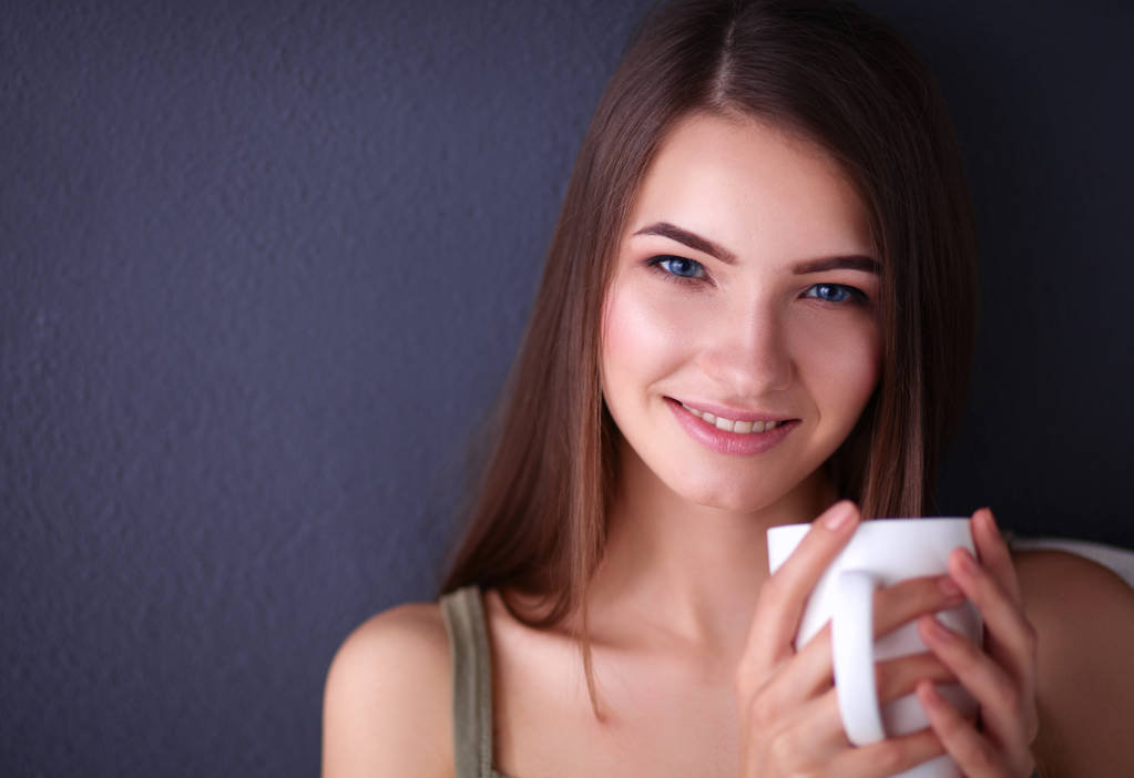 gyönyörű fiatal nő, csésze kávé barna háttér - Fotó, kép