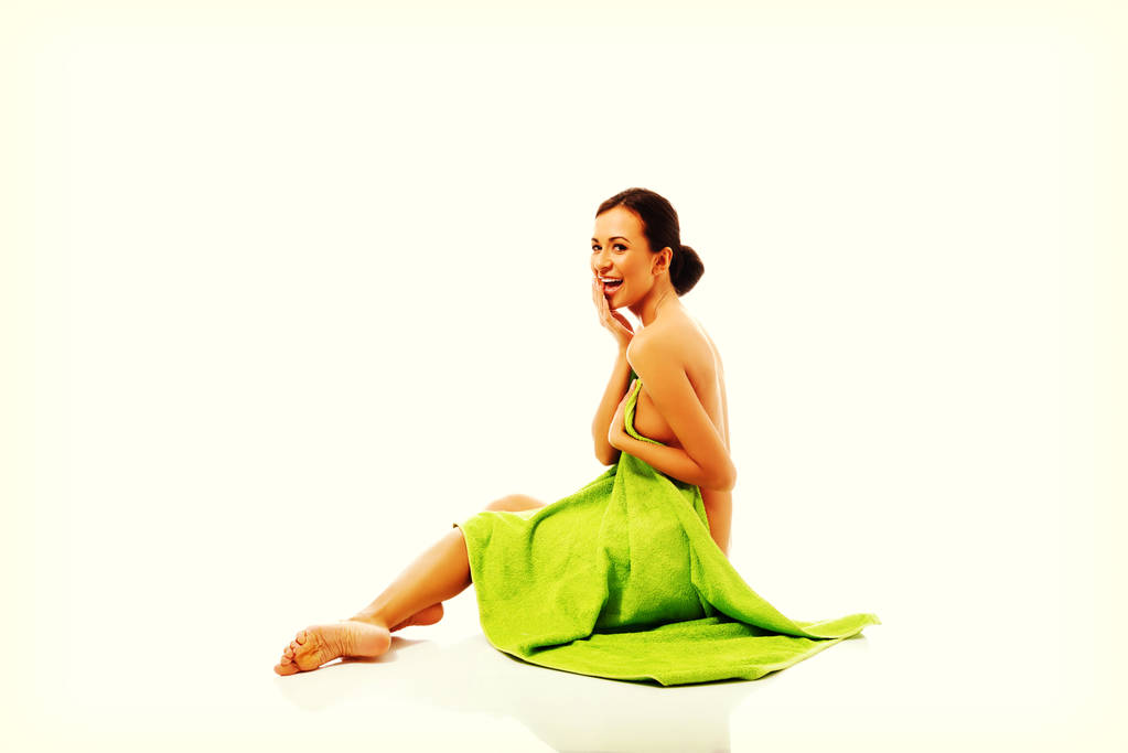 Naurava nainen istuu käärittynä pyyhkeeseen
 - Valokuva, kuva