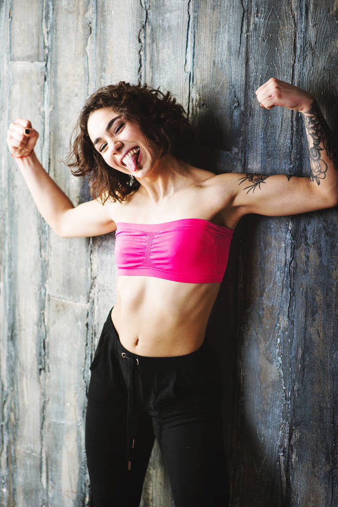 Счастливая женщина в спортивной одежде демонстрирует мускулы
 - Фото, изображение