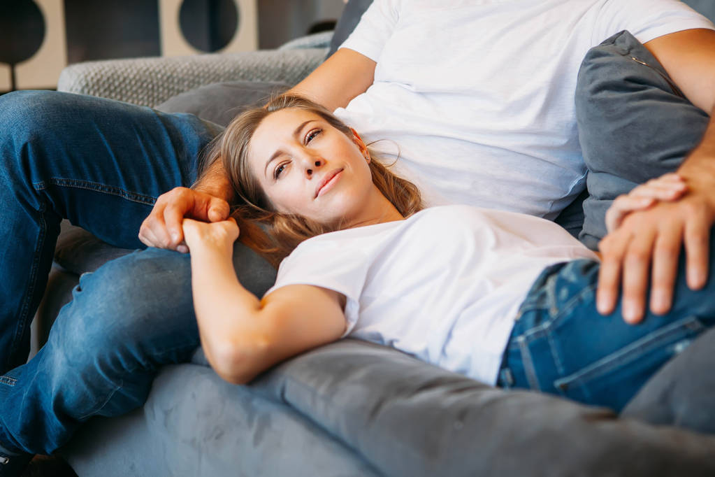 若いカップルの時間を一緒に楽しんで自宅のソファの上の男の膝の上に横になっている女性 - 写真・画像