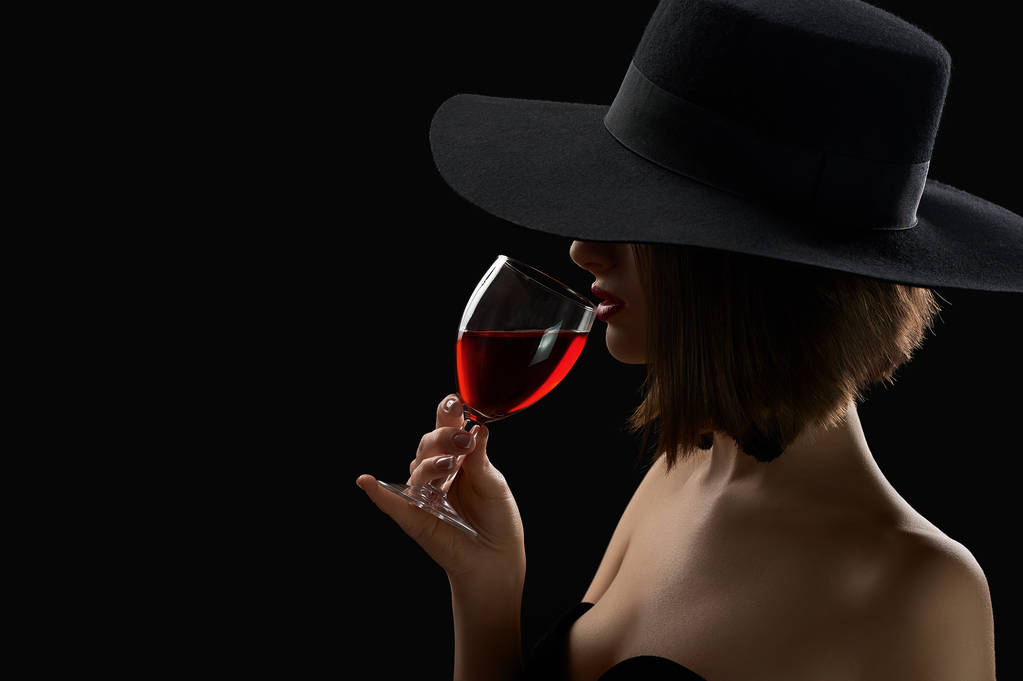 Eleganckie Tajemnicza kobieta w kapeluszu trzymając kieliszek czerwonego wina - Zdjęcie, obraz