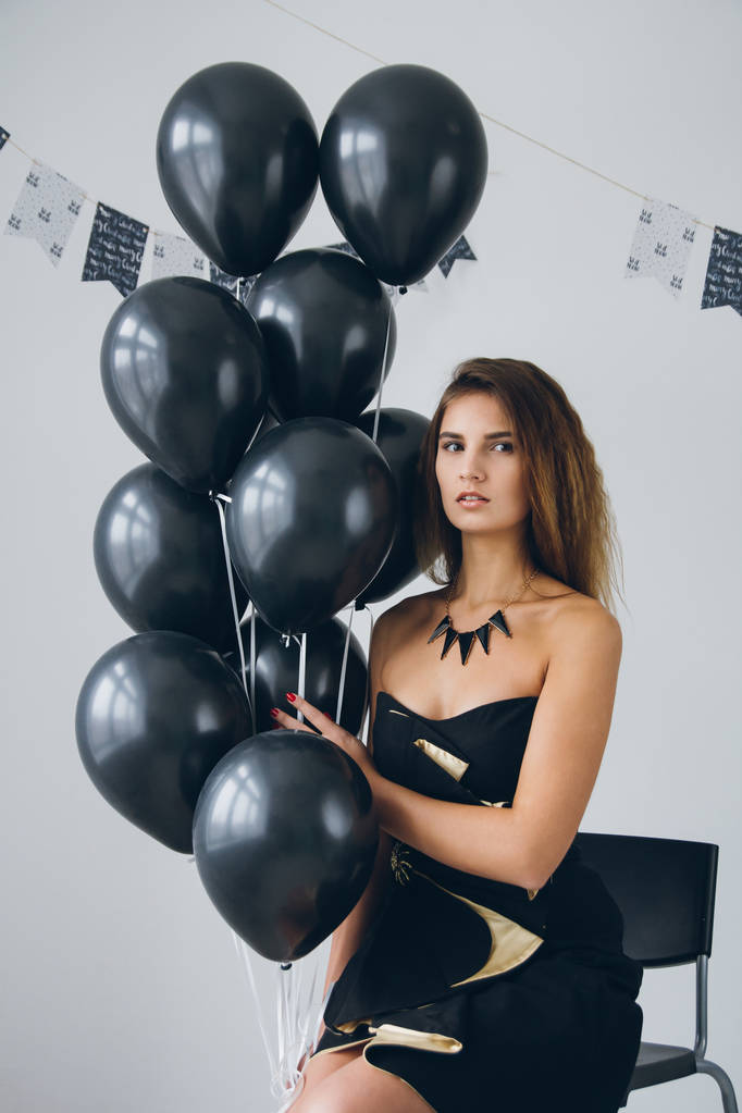 Mädchen im schwarzen Kleid mit schwarzen Luftballons - Foto, Bild