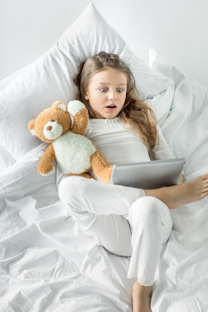 Tyttö digitaalinen tabletti sängyssä
  - Valokuva, kuva