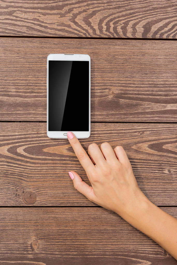 Γυναικείο χέρι χρησιμοποιώντας λευκό έξυπνο τηλέφωνο - Φωτογραφία, εικόνα