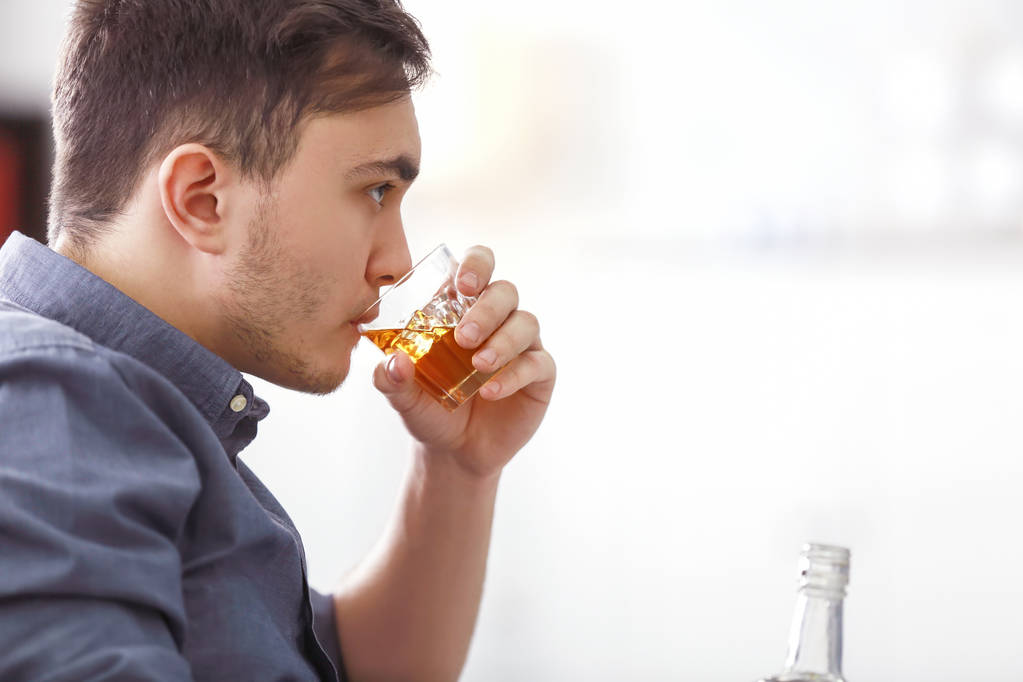 Hombre apuesto y deprimido bebiendo whisky en casa
 - Foto, Imagen