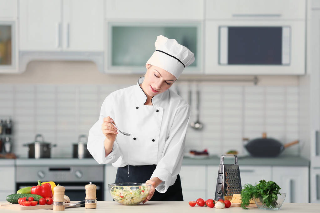 Chef feminino adicionando óleo à salada
  - Foto, Imagem