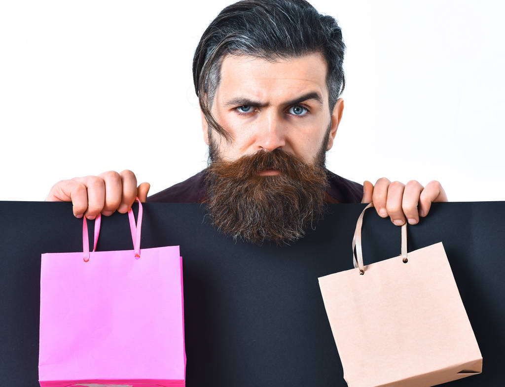 Bearded brutal caucasian hipster holding colorful package or bags - Photo, Image