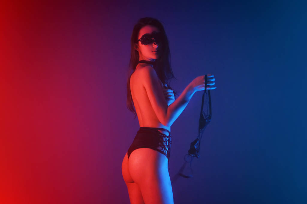 Model in verleidelijke zwarte lingerie met lichte neon gekleurde spots - Foto, afbeelding