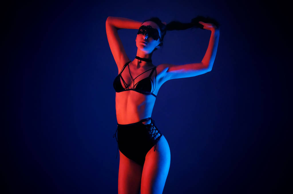 Modelo em lingerie preta sedutora com holofotes coloridos de néon claro
 - Foto, Imagem