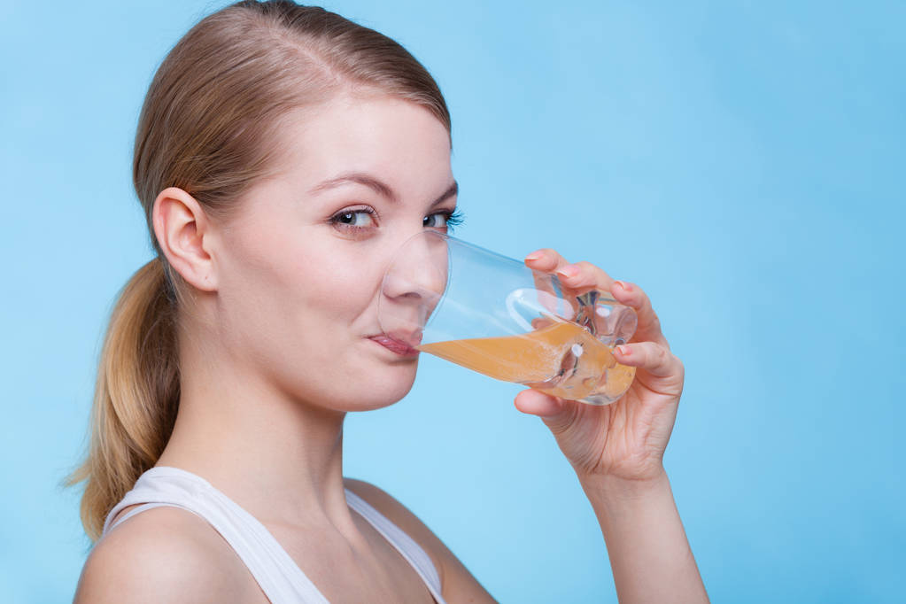 Nainen juo appelsiininmakuista juomaa tai mehua
 - Valokuva, kuva