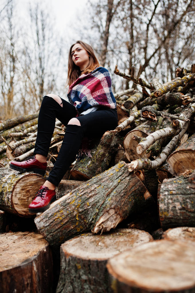 junges Hipster-Mädchen trägt Decke gegen Holzstümpfe auf Holz - Foto, Bild