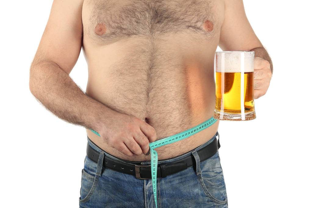 Mies mittaamassa vatsaa ja pitelemässä lasia olutta
 - Valokuva, kuva