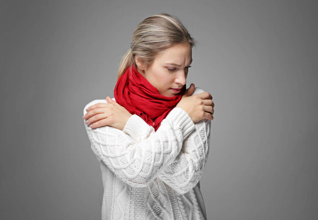 Jeune femme en vêtements chauds frissonnant de froid sur fond gris
 - Photo, image