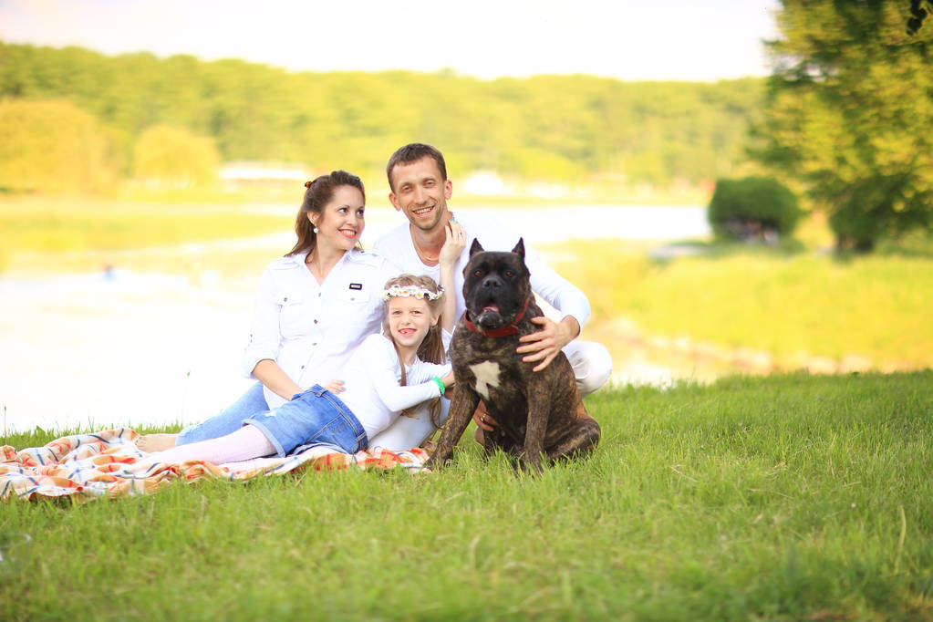 famille heureuse avec chien de compagnie au pique-nique dans une journée ensoleillée d'été. prégnent - Photo, image