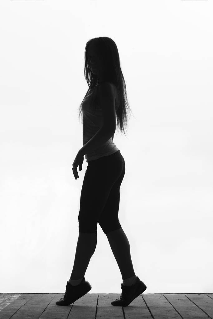 Zwart-wit silhouet van mooie jonge sportieve vrouw stand - Foto, afbeelding