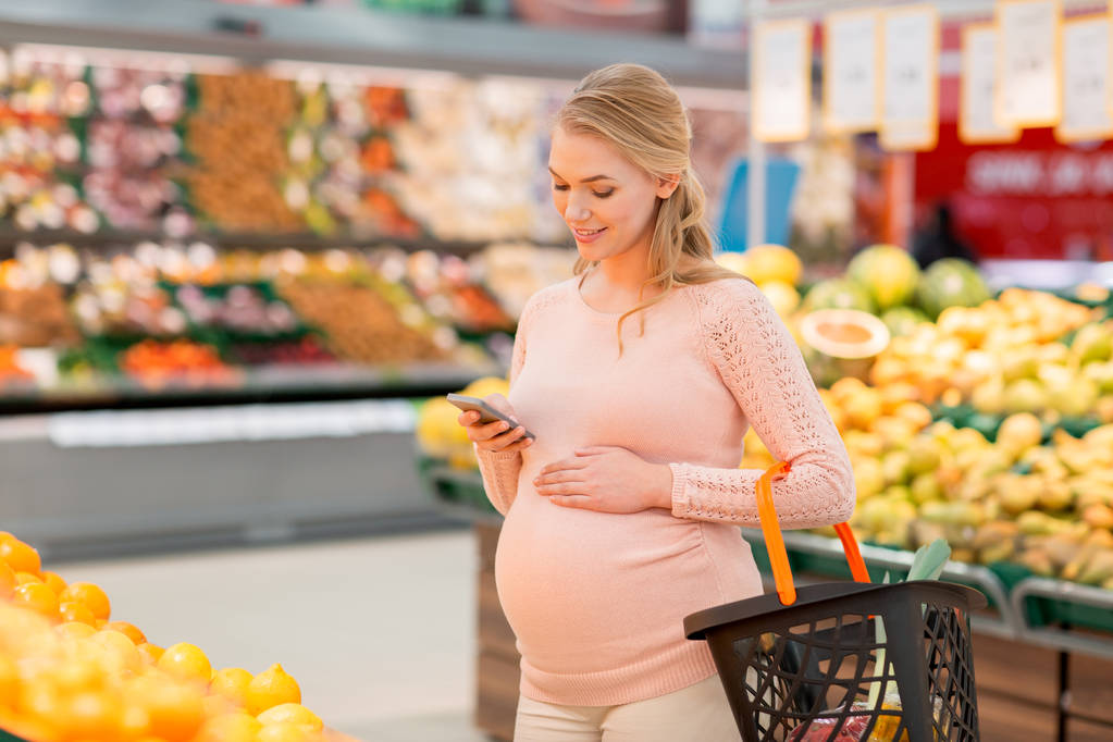 alışveriş sepeti ve smartphone ile hamile kadın - Fotoğraf, Görsel