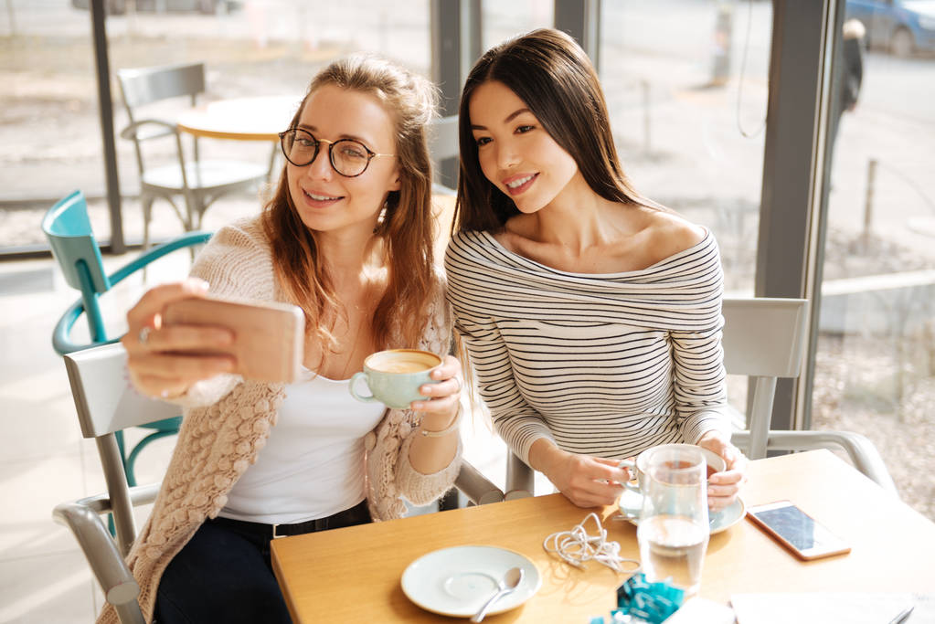 Twee vriendinnen selfies maken in het café - Foto, afbeelding