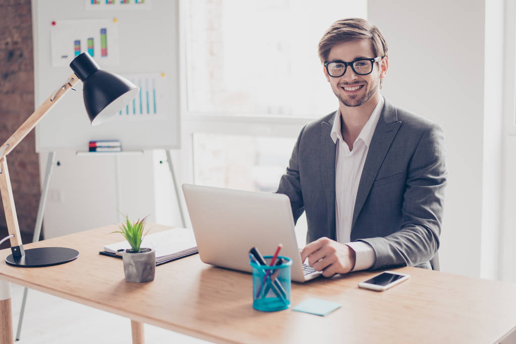 Happy young handsome businessman in glasses is sitting at desk i - Photo, Image