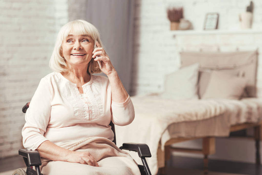 Mujer anciana con discapacidad optimista usando el teléfono en casa
 - Foto, Imagen