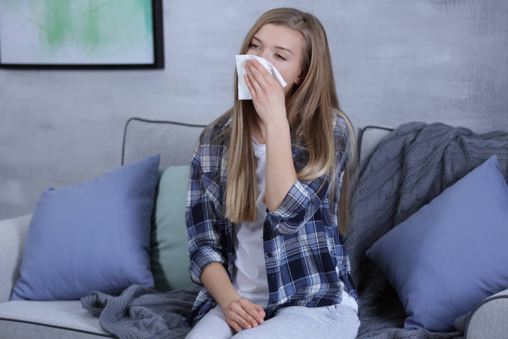 Giovane donna che soffia il naso sul tessuto a casa
 - Foto, immagini